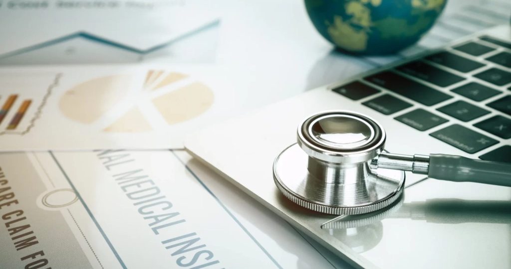 Health Insurance and Medical Coverage - Stethoscope on Laptop with Documents